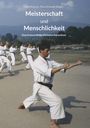 Text: "Axel Binhack, Petra Schmidt (Hrgs.) Meisterschaft und Menschlichkeit. Eine Festschrift für Efthimios Karamitsos." Menschen in Karate-Kleidung üben draußen in einer Reihe.