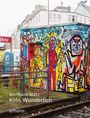 Reinhard Matz, Köln. Wunderlich, emons:. Bunt bemaltes Gebäude mit Graffiti-Figuren vor Häusern und Bahngleisen.
