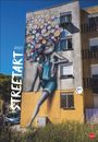 „Street Art 2027“ steht vertikal. Ein farbenfrohes Wandgemälde zeigt eine Figur mit Blumen als Haar auf einem Gebäude.