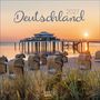 "Deutschland 2027" in eleganter Schrift. Ein Strand bei Sonnenuntergang mit Strandkörben und einer Seebrücke im Hintergrund.