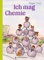 "Ich mag Chemie" von Miguel Tanco. Kinder spielen auf molekülartigen Kugeln in einer farbenfrohen Landschaft.