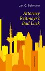 "Jan C. Behmann - Attorney Reitmayr's Bad Luck." Skyline aus gelben und orangen Gebäuden vor dunklem Hintergrund.