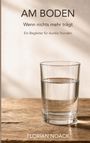 „AM BODEN. Wenn nichts mehr trägt. Ein Begleiter für dunkle Stunden.“ Ein Glas Wasser steht auf einem Holztisch.