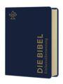 Text: "DIE BIBEL Einheitsübersetzung". Dunkelblaues Buchcover mit goldener Schrift. Oben links ein stilisiertes Logo.
