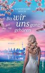 Titel: "Bis wir uns ganz gehören" von Hannelore Koch. Eine Frau im weißen Kleid blickt auf eine Skyline bei Sonnenuntergang.