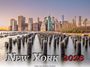 Text: "New York 2026". Skyline mit Wasser, alten Holzpfählen und Sonnenuntergang.