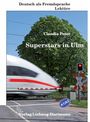 „Superstars in Ulm“ von Claudia Peter. Ein Zug überquert einen Bahnübergang, daneben eine Ampel und ein Baum im Hintergrund.