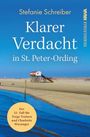 "Klarer Verdacht in St. Peter-Ording" von Stefanie Schreiber. Ein Pfahlbau am Strand mit blauem Himmel.