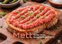 "Mett 2021 Alles wird aus Hack gemacht." Eine Scheibe Brot mit Mett und Frühlingszwiebeln garniert.