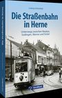 "Die Straßenbahn in Herne" von Ludwig Schönefeld. Historische Straßenbahn auf Kopfsteinpflasterstraße in einer belebten Stadt.