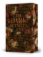 Buchcover "The Dark Between Us" von Lily Cattens mit floraler Verzierung, Taschenuhr und antikem Bücherstil.