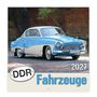 „DDR Fahrzeuge 2027“; ein blau-weißes Auto steht vor einer Ziegelmauer unter Bäumen.
