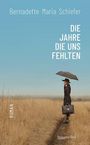 "Die Jahre die uns fehlten" von Bernadette Maria Schiefer. Eine Frau mit Regenschirm steht auf einem Feldweg.