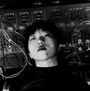 Texte: "In the Air 中飞人". Eine Person liegt vor einem komplexen Musik-Synthesizer mit vielen Kabeln.