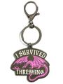 Ein Schlüsselanhänger mit der Aufschrift „I SURVIVED THRESHING“ und einer lila Drachenillustration.