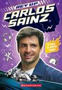 "Rev Up Carlos Sainz", "8 Pages of Photos Inside!" Ein Fahrer steht im Vordergrund vor Rennwagen-Illustration und Symbolen.