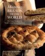 Text: Mastering Breads of the World. Grobes Brot mit schwarzem Sesam und hellbrauner Kruste, Person im Hintergrund.