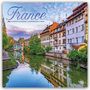 "La France 2027 16-Month Calendar. Malerische Fachwerkhäuser am Fluss mit Spiegelung, umgeben von Bäumen und blauem Himmel."