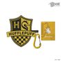 Text: „Hufflepuff“. Ein Wappen mit einem Dachs und gelb-schwarzen Details. Anhänger und Notizblock sichtbar.