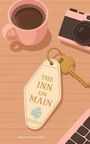 „THE INN ON MAIN“ auf einem Schlüsselanhänger. Daneben eine rosa Kaffeetasse, Kamera und Computertastatur.