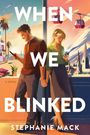 Titel: "WHEN WE BLINKED". Autorin: Stephanie Mack. Ein Mann und eine Frau, die getrennt durch eine Scheibe auf Handys schauen. Im Hintergrund Palmen und Berge.