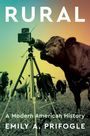 "RURAL - A Modern American History - EMILY A. PRIFOGLE." Eine Kuh schaut in eine Kamera auf einem Stativ, mit Kühen im Hintergrund.