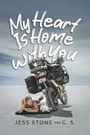 "My Heart Is Home With You" in handschriftlichem Stil. Eine Frau und ein Hund ruhen unter einem Motorrad auf sandigem Boden.