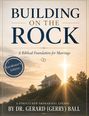 "BUILDING ON THE ROCK" zeigt ein Haus auf einem Hügel bei Sonnenuntergang mit einem leuchtenden Kreuz darüber.