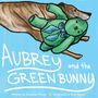 „Aubrey and the Green Bunny“ steht in großen, weißen Buchstaben. Ein Hund trägt einen grünen Hasen auf einem blauen Hintergrund.